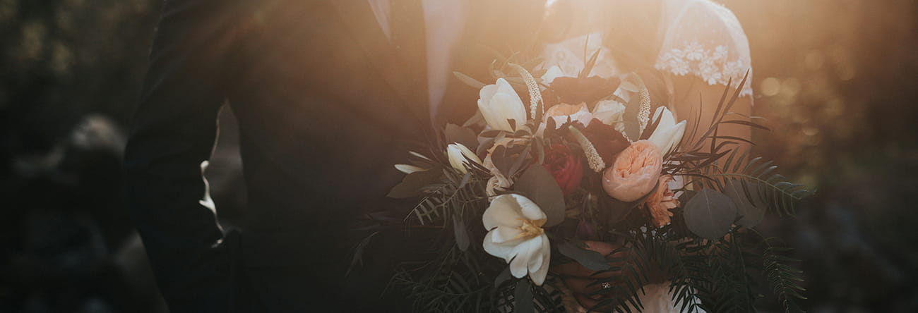 A sillouhette of a bride and groom with a bouquet.