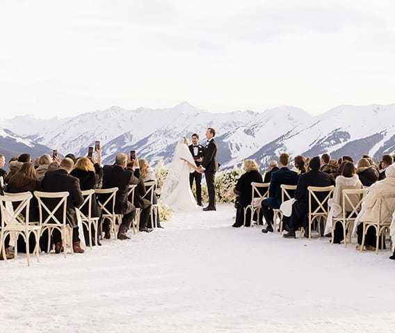 A winter wedding ceremony at the wedding overlook with snowcapped mountains in the background.