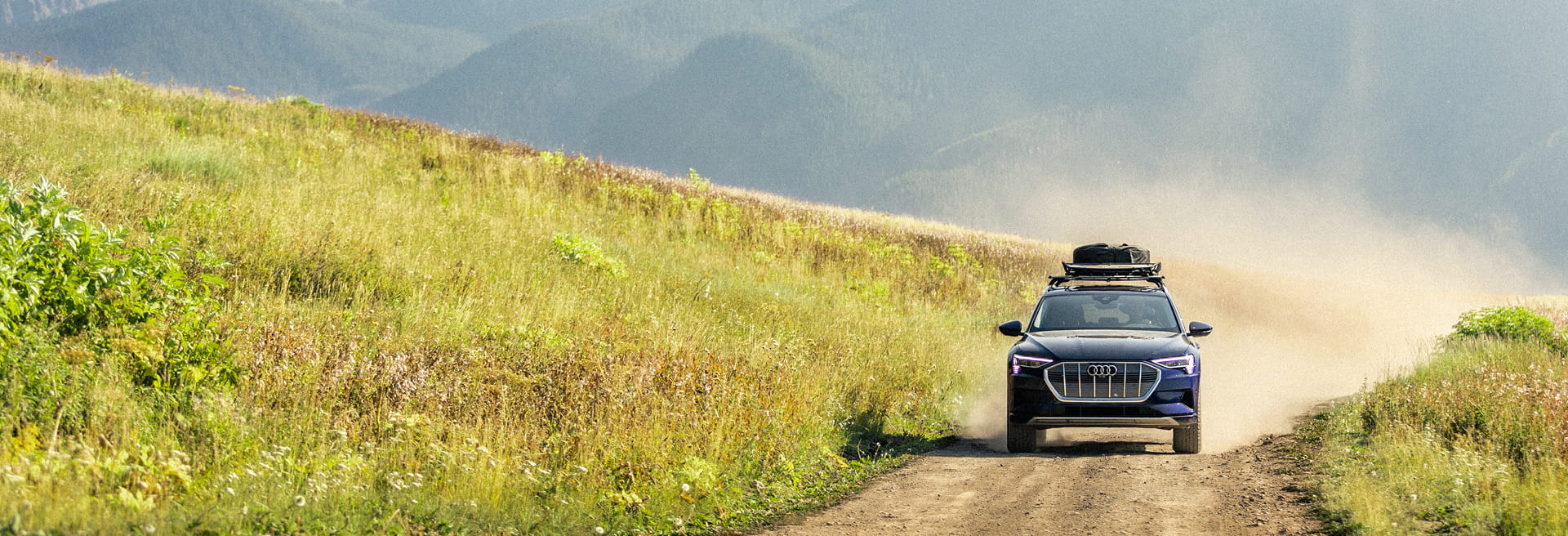 audi car driving on road in front of mountains