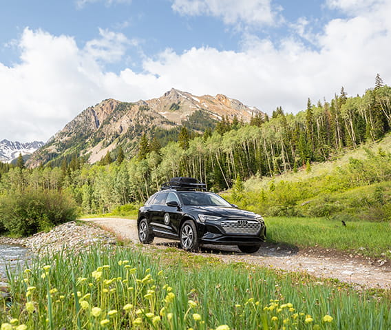 A Little Nell Audi driving down the road in the mountains in summer.
