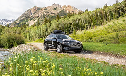 A Little Nell Audi driving down the road in the mountains in summer.