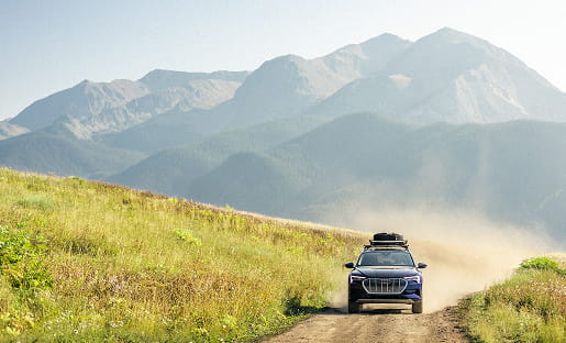 audi car driving on road in front of mountains