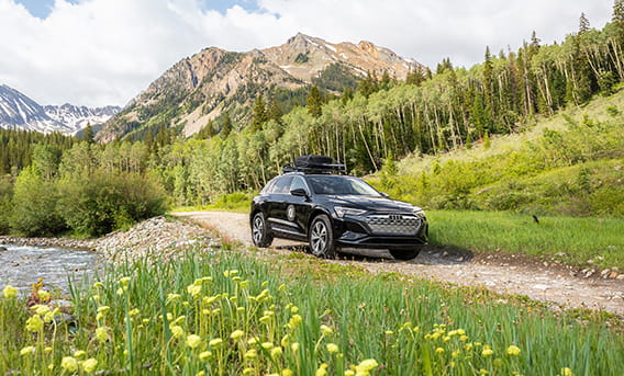 A Little Nell Audi driving down the road in the mountains in summer.
