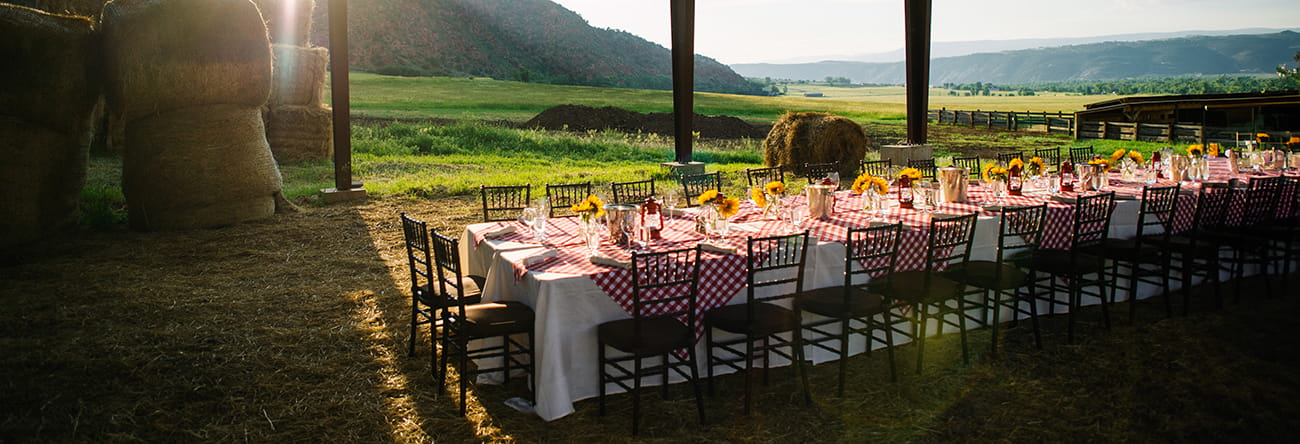 A ranch in the roaring fork valley with a banquet table set on the farm at sunset.