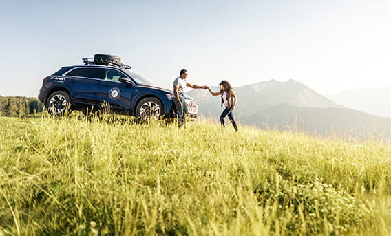 a couple walking in front of an audi on aspen mountain