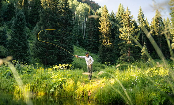 A man fly-fishing on The Little Nell adventure center's private pond.