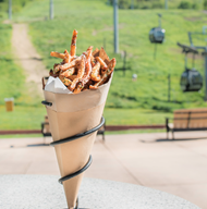 Ajax Tavern's famous truffle fries served in a cone with views of the gondola in the background.