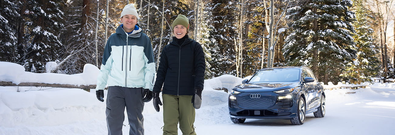 two people snowshoeing in front of audi car