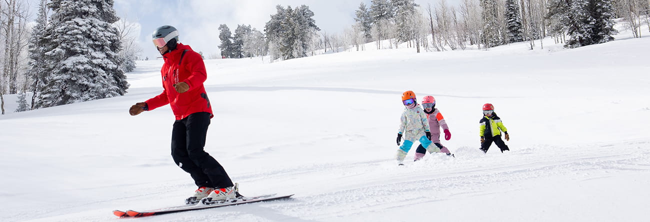 Children and an instructor skiing during ski school.