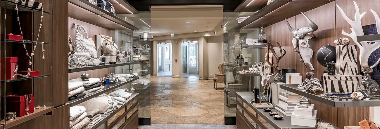 The inside of the boutique at The Little Nell with novel items on the shelves and the lobby through the doorway.