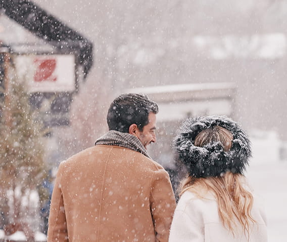 couple walking in snowy downtown aspen