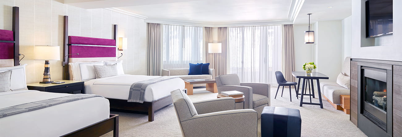 Spacious double queen room with desk, TV, and fireplace.