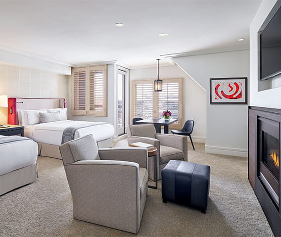 Spacious double queen room with fireplace lit and snow covered trees outside the window.