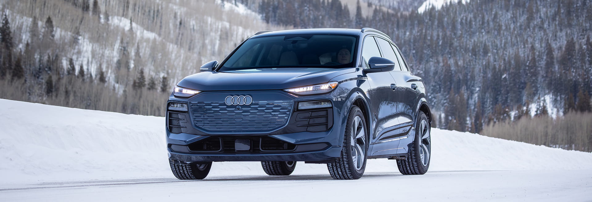 audi car driving on road in front of mountains