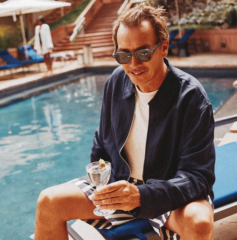 man with drink by pool