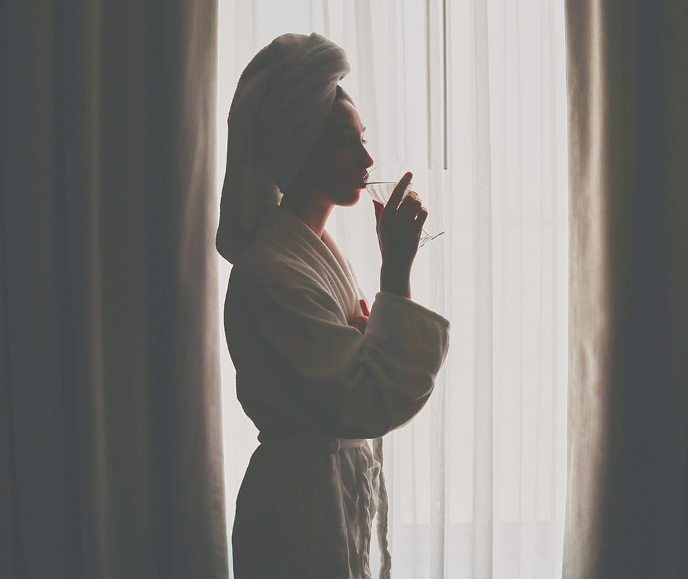 woman in robe in front of window