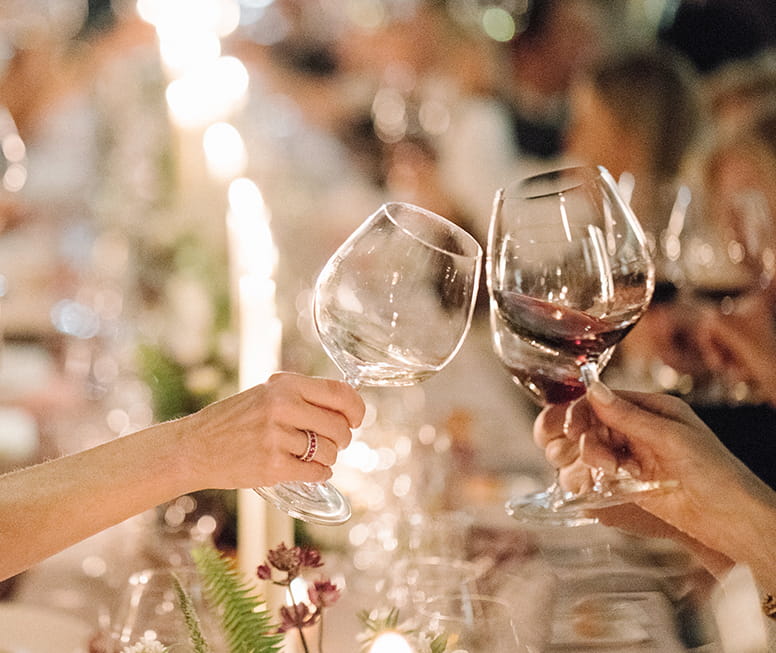 people cheerings wine glasses at table